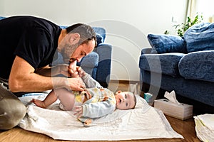 Father changing his baby`s diaper while caressing him affectionately