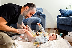 Father changing his baby`s diaper while caressing him affectionately