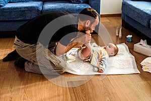 Father changing his daughter`s dirty diaper on the living room floor photo