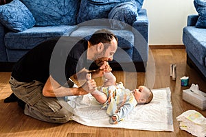 Father changing his daughter`s dirty diaper on the living room floor photo