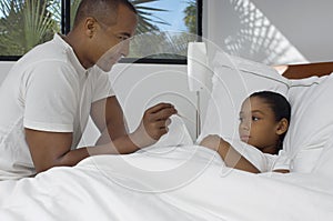 Father Checking Daughter's Temperature In Bed