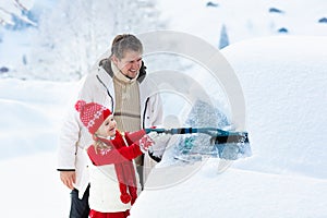 Father and child brushing off car in winter