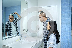 Father and child combing hair in front of the mirror