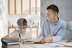 Father and child are doing homework.Young teacher tutor is studying with boy.Boy teenager in glasses writes in notebook