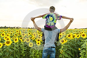 Father with child in a field of blooming sunflowers , father`s day