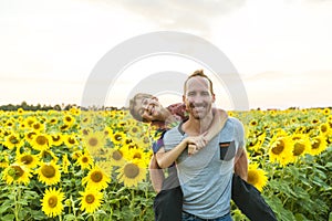 Father with child in a field of blooming sunflowers , father`s day