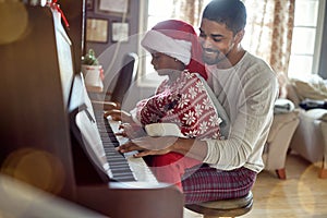 Father with child girl on Christmas play music on piano