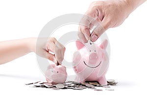 Father and child hand put coin to piggy bank isolated