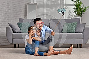 father and child holding paper glasses on stick and take a selfie