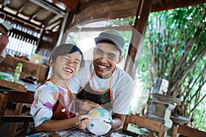 Father and child painting pottery goods