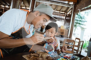 Father and child painting pottery goods