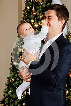 Father and child play Christmas. Dad holds a boy in his arms in white sliders. Business father.