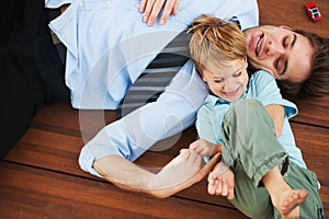 Father, child and playing on floor with happy, family home and support of businessman with kid. Man, kid and game in