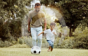 Father, child and playing with soccer ball in the park for fun quality bonding time together in nature. Dad and kid