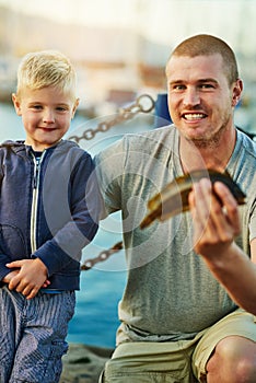 Father, child and portrait with fish or proud for first catch or son bonding on vacation, harbor or teach. Man, kid and