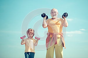Father and child training together. Grandfather and child lifting dumbbell. Healthy lifestyle. Grandfather and little