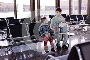 Father and child wearing protective masks in a public place. family dad son at airport awaits departure for the covid-19 pandemic