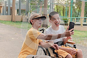 Father and child on wheelchair using some mats phone