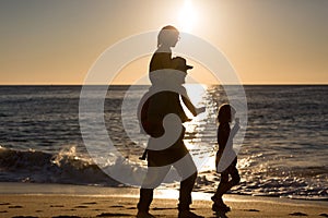 Father and children on the beach during sunset photo