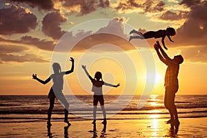 Father and children playing on the beach at the sunset time.