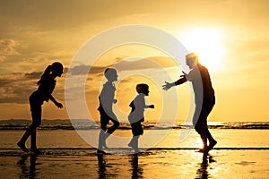 Father and children playing on the beach at the sunset time.