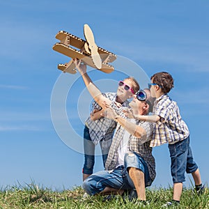 Father and children playing with cardboard toy airplane in the p