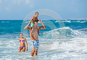 Father and children playing in the sea
