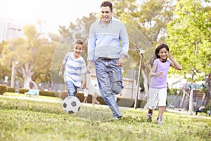 Father With Children Playing Soccer In Park Together