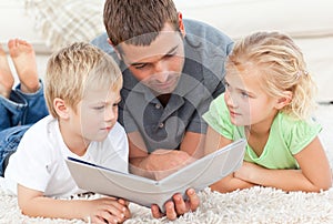 Father and children reading a book on the floor