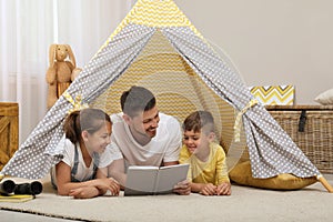 Father with children reading book in wigwam