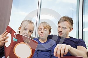 Father and children reading storybook at home