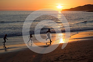 Father and children running on the beach during sunset, Praia da Luz, Portugal