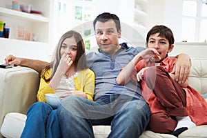 Father And Children Sitting On Sofa Watching TV Together