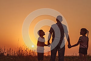 Father and children standing in the park at the sunset time