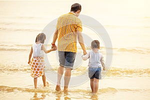 Father And Children  walking into the  Beach Holiday .  two kids one dad . rear back view