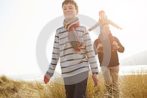 Father And Children Walking Through Dunes On Winter Beach