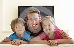 Father And Children Watching Widescreen TV At Home