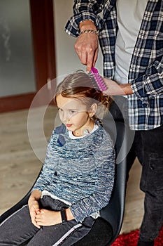 Father combing, brushing his daughter& x27;s hair at home