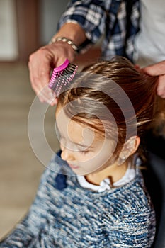 Father combing, brushing his daughter's hair at home