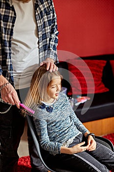 Father combing, brushing his daughter`s hair at home