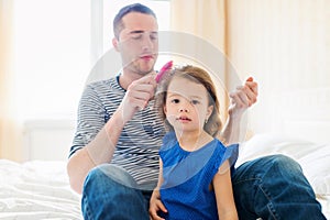 Father combing hair of his daughter in the morning