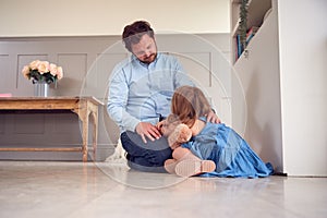 Father Comforting Unhappy Daughter Sitting On Floor Holding Teddy Bear