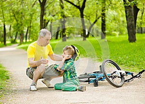 Father comforts his son that fell from the bike