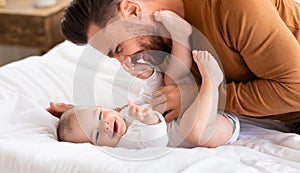 Father Cuddling Bonding With Little Baby Lying On Bed Indoor