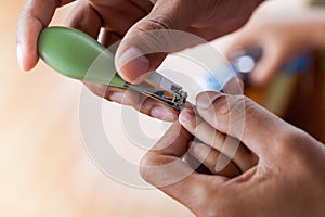 Father cutting fingernails for his baby on wooden table