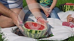 Father Cutting Watermelon to Children Outdoors