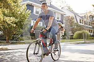 Father Cycling Along Street With Daughter In Child Seat