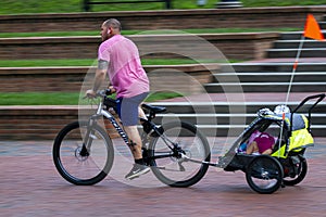 A father is cycling home with his kids on child trailer