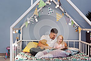 Father dad in bed with daughter reading stories at bedtime