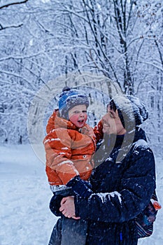 Father and his son playing outside, winter forest on the background, snowing, happy and joyful